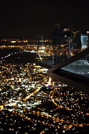 several people on glass patio of a skyscraper during night