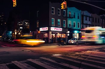 several vehicle passing by Pizza store