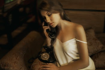Sexy young girl hold a telephone sitting on sofa