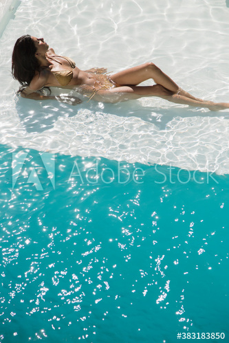 Sexy young woman sunbathing in sunny summer swimming pool