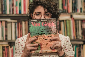 Shallow Focus Photo of a Woman Holding Van Gogh Book