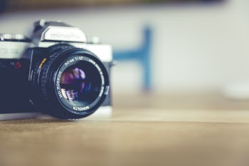 Shallow Focus Photo of Dslr Camera on Brown Wooden Table