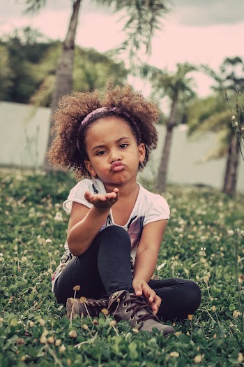 Shallow Focus Photo of Girl Sitting on Grass