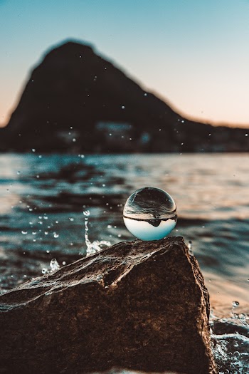 Shallow Focus Photo of Glass Ball Near Body of Water