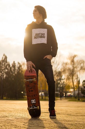 Shallow Focus Photo of Man in Black Pullover Hoodie Holding Red Skateboard