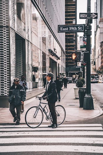 Shallow Focus Photo of Man Standing Beside Gray Bike on Crosswalk
