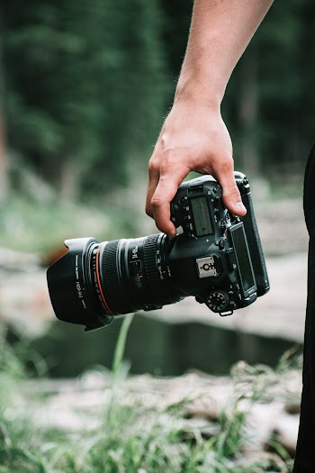 Shallow Focus Photo of Person Holding Black Dslr Camera