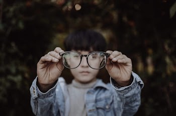 Shallow Focus Photo of Person Holding Black Framed Eyeglasses