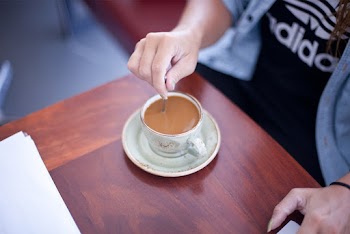 Shallow Focus Photo Of Person Mixing Brown Liquid In White Ceramic Mug