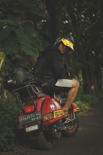 Shallow Focus Photo of Person Riding Red Motor Scooter