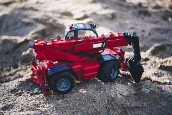 Shallow Focus Photo of Red Front-loader Toy on Gray Sand