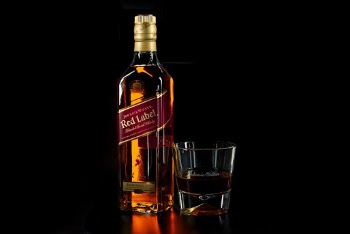 Shallow Focus Photo of Red Label Liquor Bottle Beside Drinking Glass