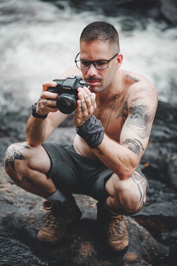 Shallow Focus Photo of Topless Man Using Black Dslr Camera