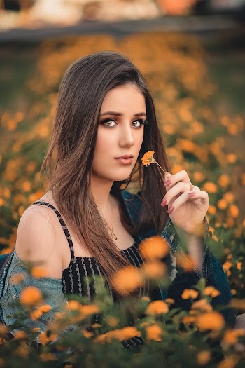 Shallow Focus Photo of Woman Holding an Orange Flower