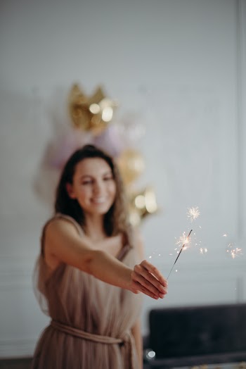 Shallow Focus Photo of Woman in Brown Sleeveless Dress Holding Sparkle
