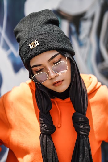 Shallow Focus Photo of Woman in Orange Pullover Hoodie Wearing Black Knit Cap