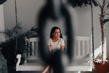 Shallow Focus Photo of Woman in White and Orange Striped T-shirt Sitting on Swing Bench