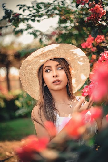 Shallow Focus Photo of Woman Standing Beside Pink-petaled Flowers