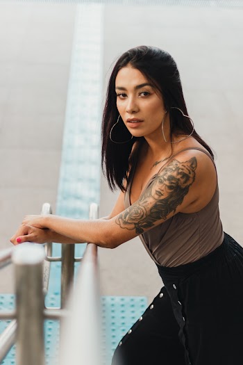Shallow Focus Photo of Woman Standing in Front of Stainless Steel Stair Rail