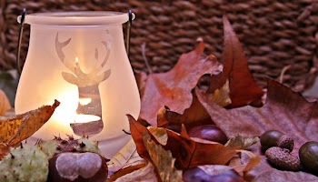 Shallow Focus Photograph Clear Reindeer Print Candle Glass Candle Lamp Near Red Dried Leaf