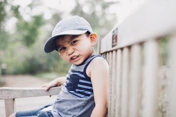 Shallow Focus Photography Of A Boy Sitting On Bench