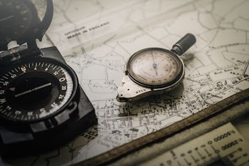 Shallow Focus Photography of Black and Silver Compasses on Top of Map