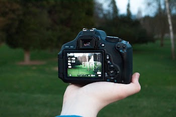 Shallow Focus Photography of Black Dslr Camera on Person's Right Hand