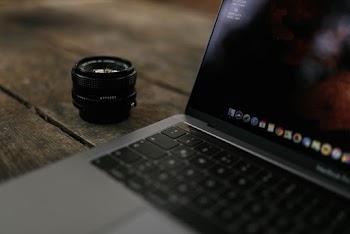Shallow Focus Photography Of Black Zoom Lens Beside Macbook Pro