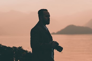 shallow focus photography of man holding DSLR camera