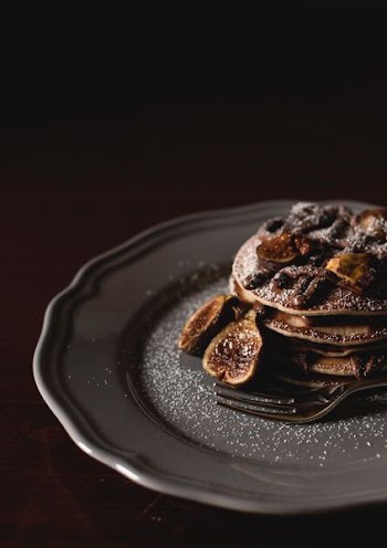 shallow focus photography of pan cakes with slices of banana and syrup on top on gray plate