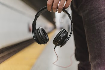 Shallow Focus Photography of Person Holding Headphones