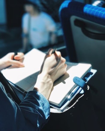 shallow focus photography of person writing on book