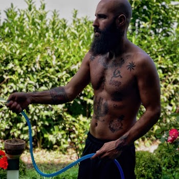 Shallow Focus Photography Of Topless Man Holding Water Hose