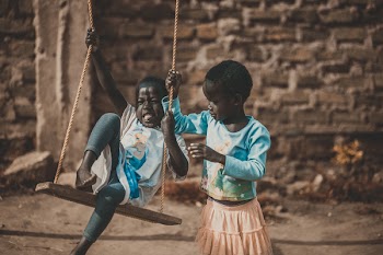 Shallow Focus Photography of Two Kid Playing on Swing