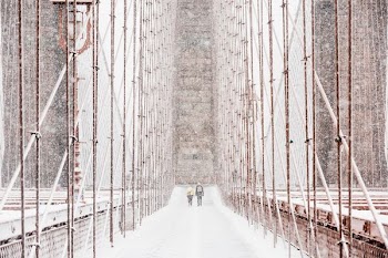 shallow focus photography of two person waling on snowy brimdge