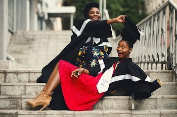 Shallow Focus Photography of Two Women in Academic Dress on Flight of Stairs