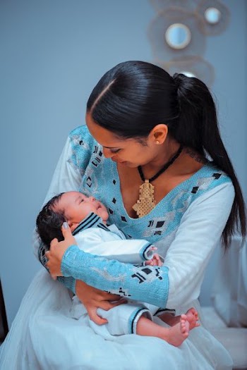 shallow focus photography of woman carrying baby