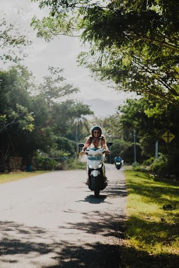 shallow focus photography of woman driving motorcycle at the road