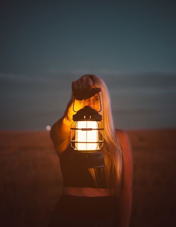 shallow focus photography of woman holding lantern