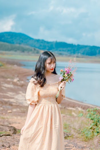 Shallow Focus Photography of Woman in Beige Off-shoulder Dress Holding Bouquet of Flowers