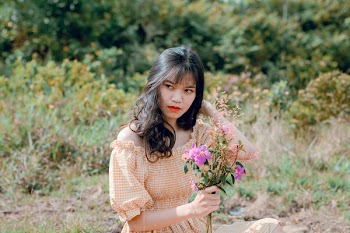 Shallow Focus Photography of Woman in Beige Off-shoulder Dress Holding Bouquet of Flowers