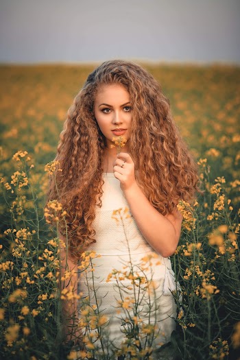 Shallow Focus Photography of Woman in White Dress Holding Yellow Flower