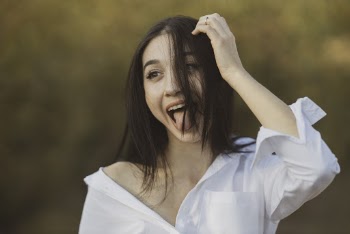 Shallow Focus Photography of Woman Showing Her Tongue While Touching Her Hair