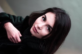 shallow focus photography of woman showing smile while holding coat