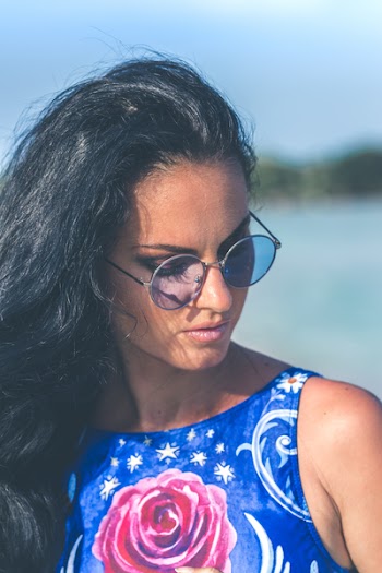 Shallow Focus Photography of Woman Wearing Blue Floral Sleeveless Top and Black Sunglasses With Gray Frames