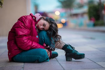 Shallow Focus Photography Of Woman Wearing Red Puffer Jacket Sitting On Sidewalk