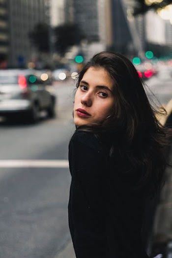 shallow focus photography of woman with cars in background
