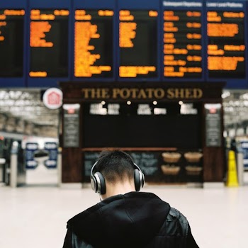 shallow photography of man using wireless headphones