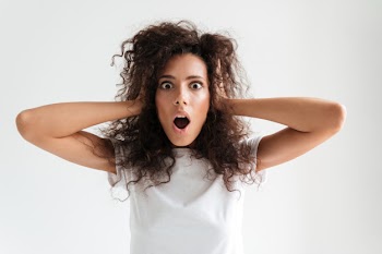 Shocked astonished young woman keeping hands on her head Free Photo