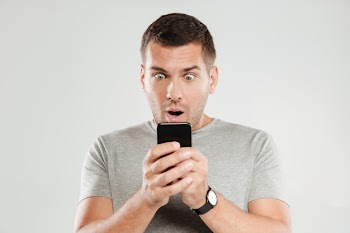 Shocked man chatting by mobile phone. Free Photo